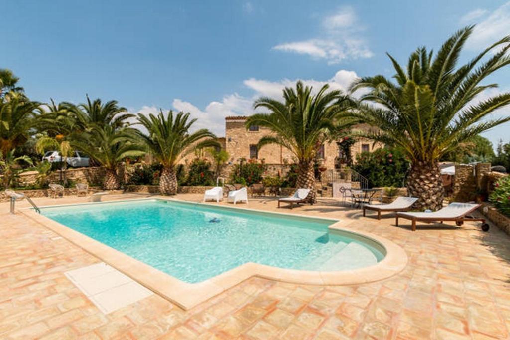 a swimming pool in a yard with palm trees at VILLA NISCEMI vicino Piazza Armerina e Caltagirone in Niscemi