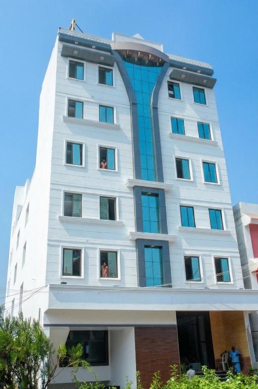 a tall white building with people in the windows at MGR Residency in Pondicherry