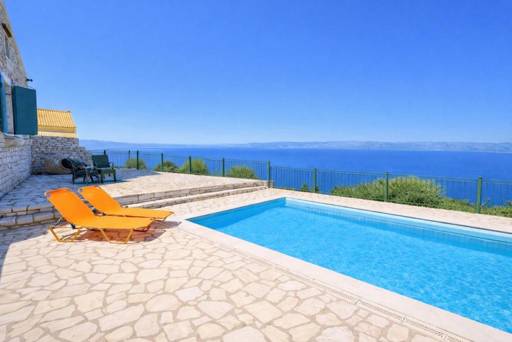 a swimming pool with two chairs and the ocean at Villa Agathi in Anemogiannátika