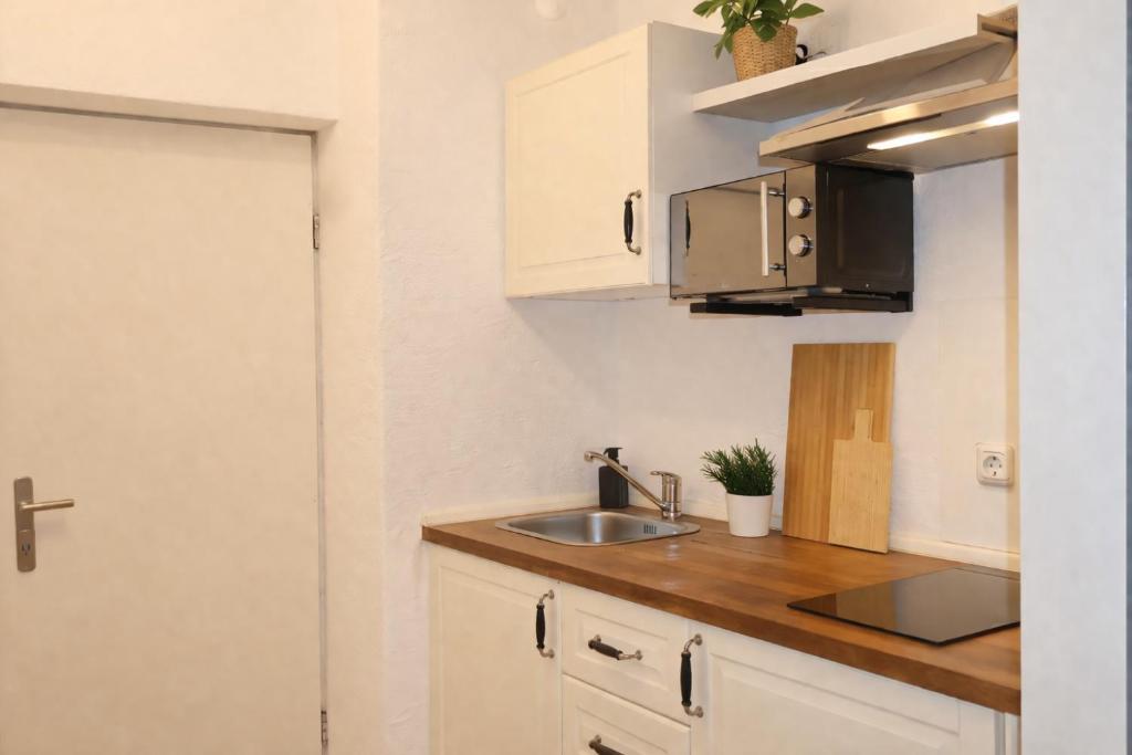 a kitchen with white cabinets and a sink at Exklusive Studio-Apartments mit Balkon in Bad Rothenfelde