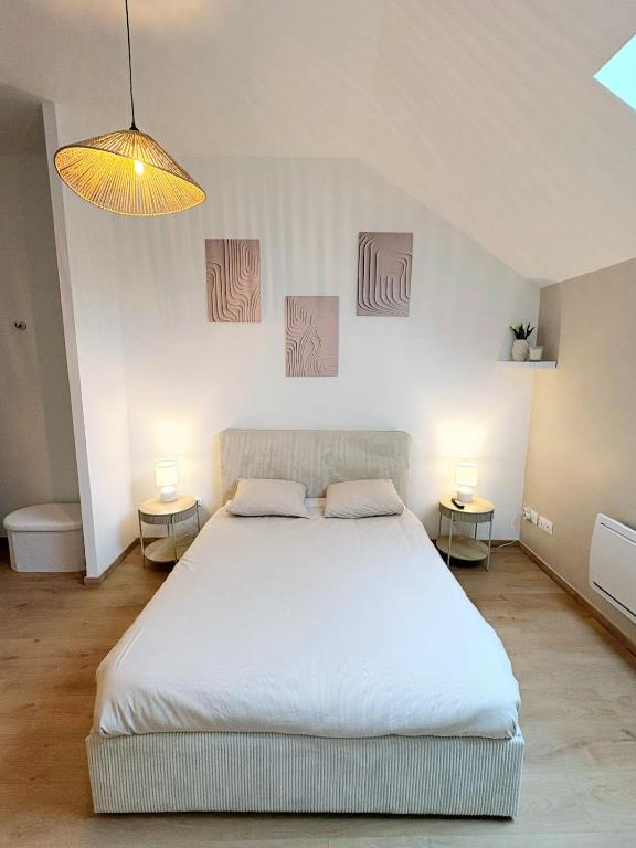 a bedroom with a large white bed with two tables at Studio Prestige, Cocon de Charme & Confort in Saint-Quentin