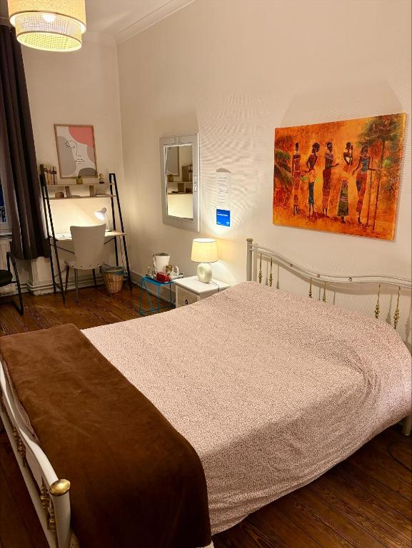 a bedroom with a bed and a painting on the wall at vaste chambre familiale in Bourg-en-Bresse