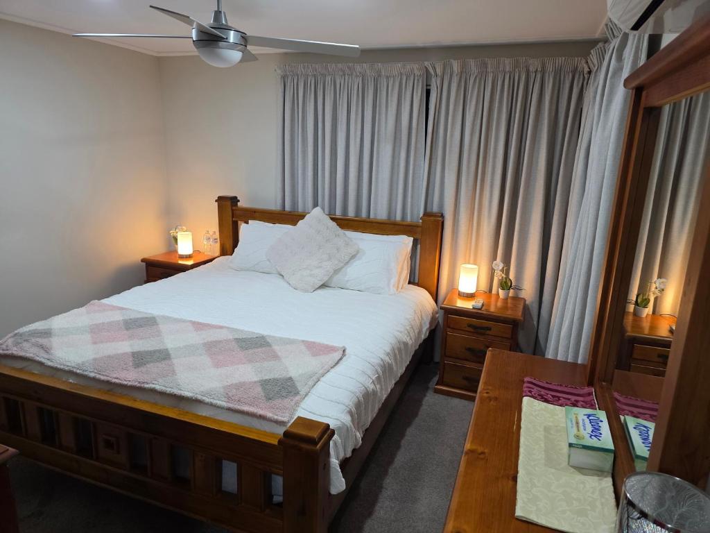a bedroom with a bed and two tables and a window at Sunset Beach B&B in Waggrakine