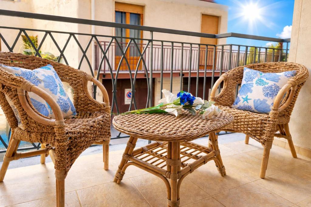 two wicker chairs and a table with flowers on it at Cavalluccio Marino-Central-with Balcony by Gessica Holiday in Polignano a Mare