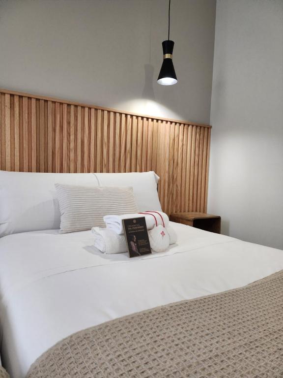 a bedroom with a white bed with a book on it at CREDENCIAL Bulevar in Sarria