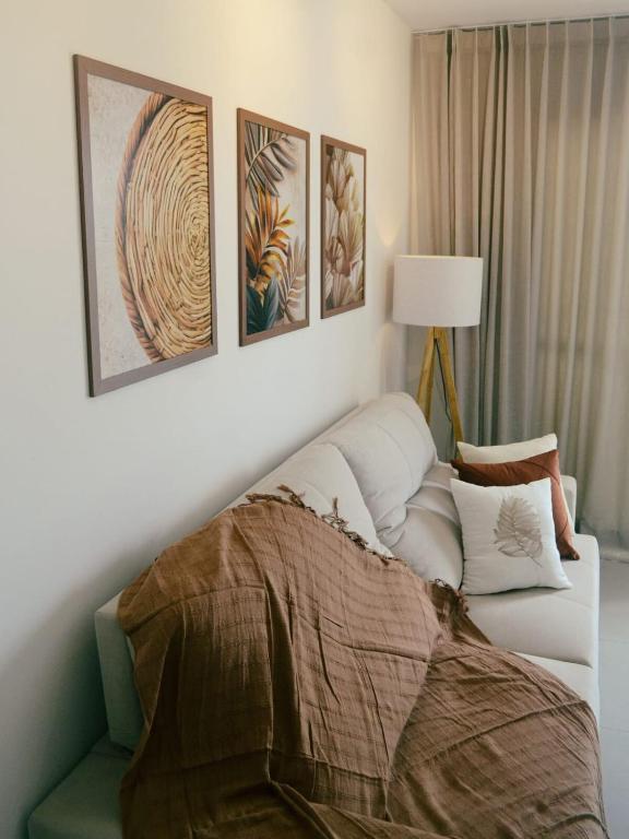 a living room with a white couch and four paintings at Airport subway apartment in Lauro de Freitas