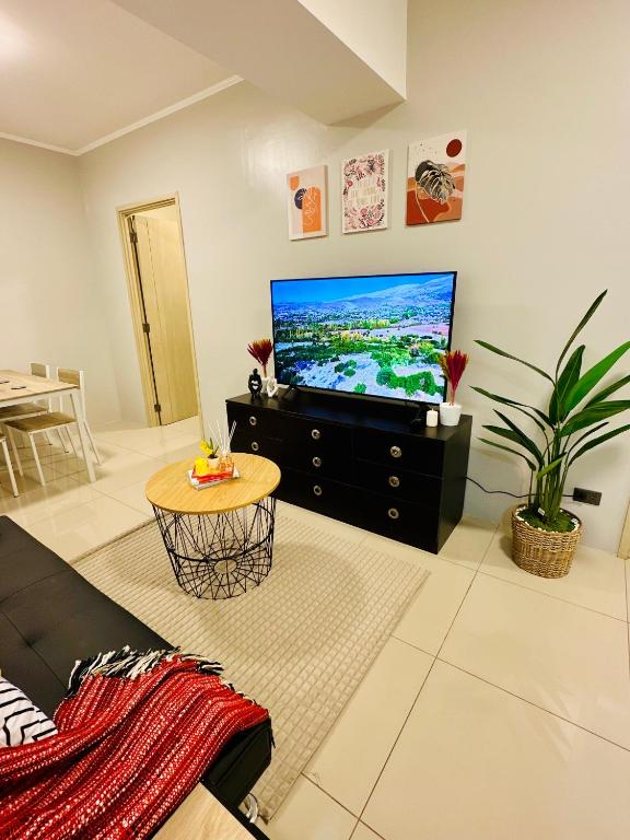 a living room with a flat screen tv and a table at Aeva's Cozy Stays in Manila