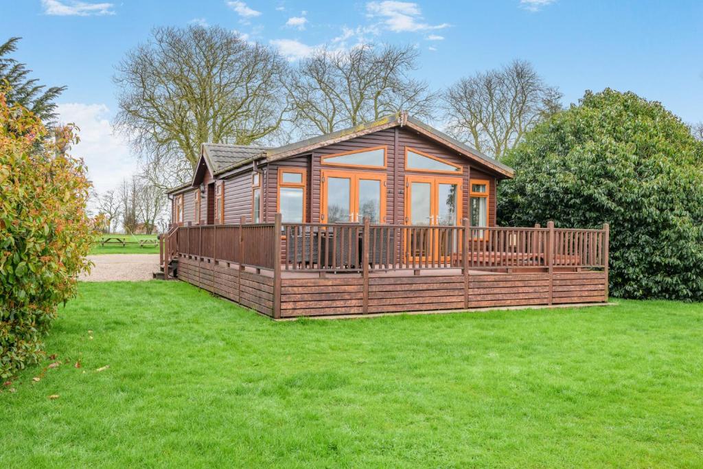 a small wooden cabin with a large deck in a field at Field View 2 bed 'S'- Spruce in Eye