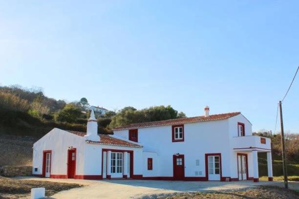 a large white house with red shuttered windows at Marvão Country Houses - Queixos II in Santo António das Areias