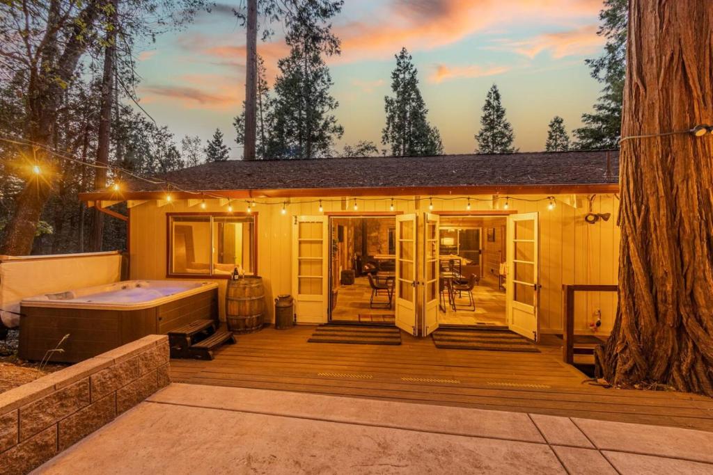 a small house with a hot tub and a deck at Enchanted Pines in Twain Harte