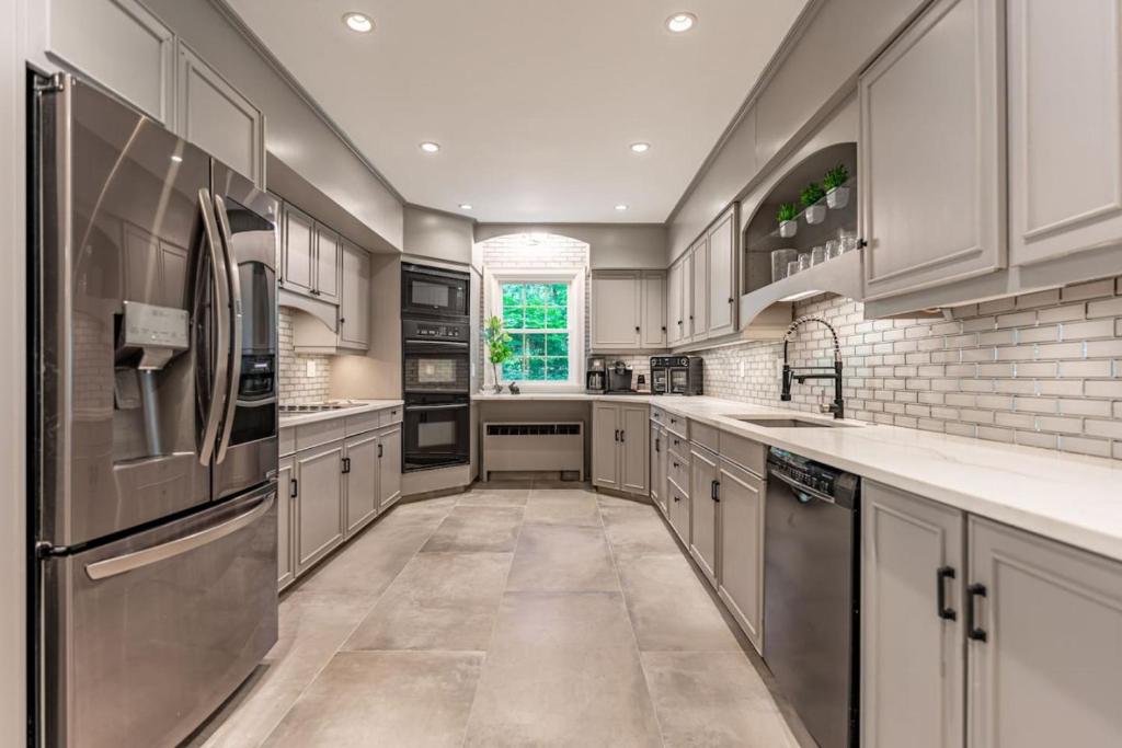 a large kitchen with white cabinets and stainless steel appliances at Chic Modern Glam in Rockford