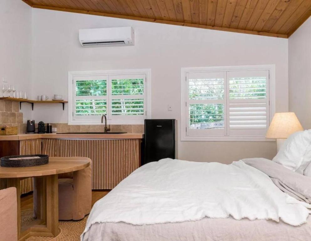a bedroom with a bed and a kitchen at Sanctuary Spaces - Sunset Bungalow 101 in Byron Bay