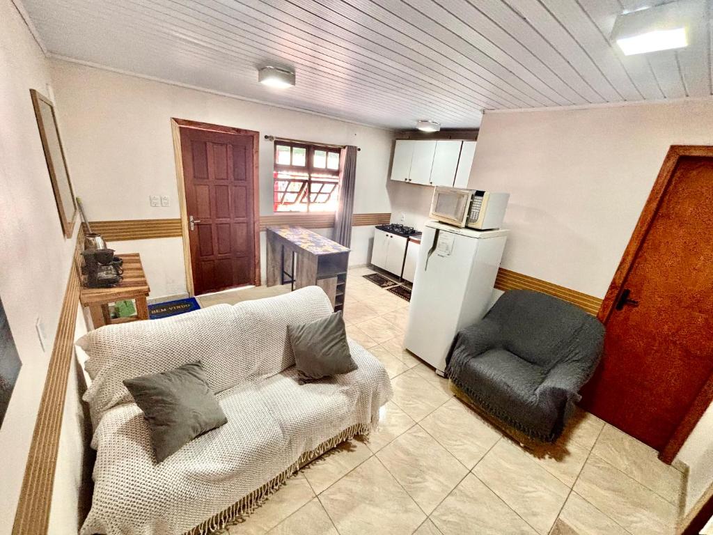 a living room with a couch and a kitchen at Refúgio da Serra - Apto Completo a 3 minutos do centro de Canela in Canela