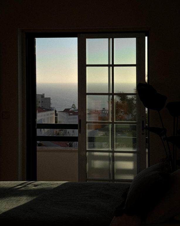 a bedroom with a view of the ocean through a glass door at The Salty Nap in Ericeira