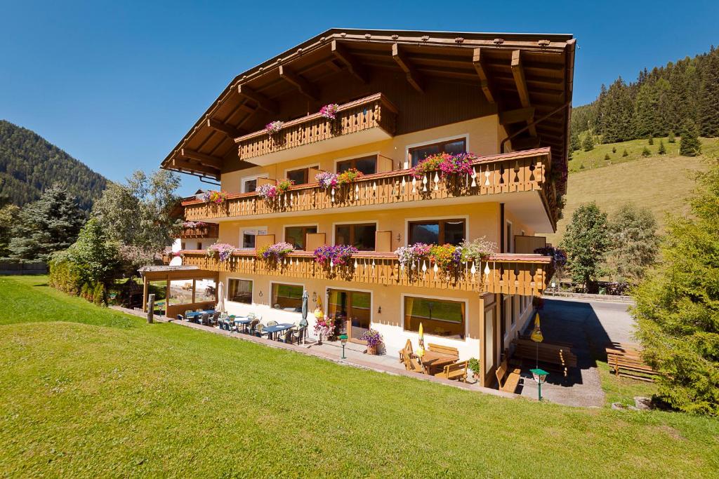 ein großes Gebäude mit einem Balkon mit Blumen darauf in der Unterkunft Zirbenhof in Innerkrems