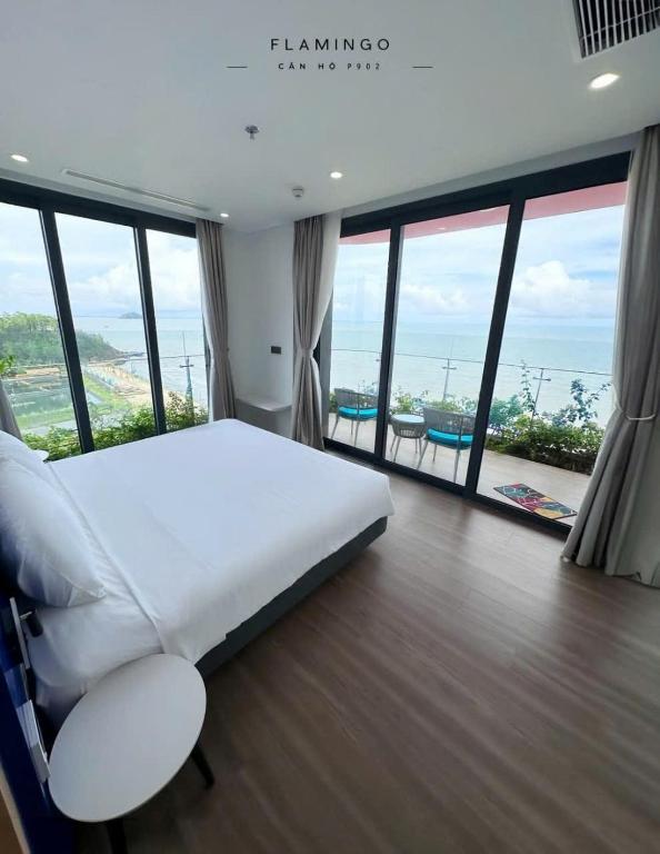 a bedroom with a large white bed and large windows at Flamingo Hai Tien Beach Resort in Thanh Hóa