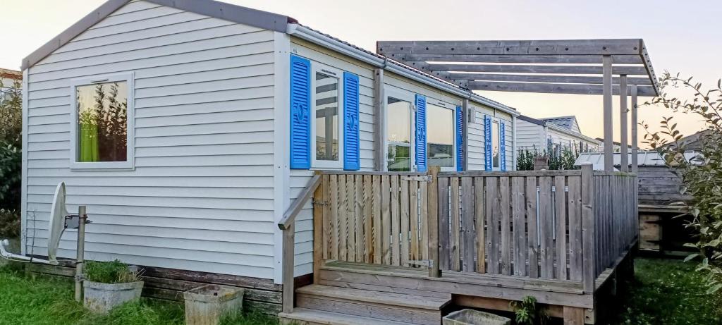 a house with blue shutters and a wooden deck at Mobile Home privé dans camping n 69 in Port-Bail-sur-Mer