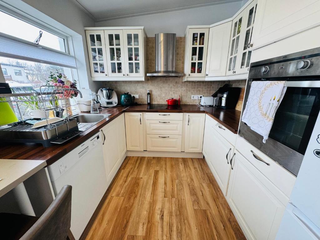 a kitchen with white cabinets and a wooden floor at Langafit Guest house in Garðabær