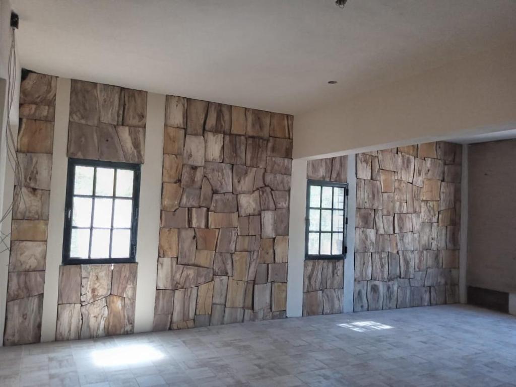 a room with two windows and a stone wall at Hostel Waysanú in Capilla del Monte