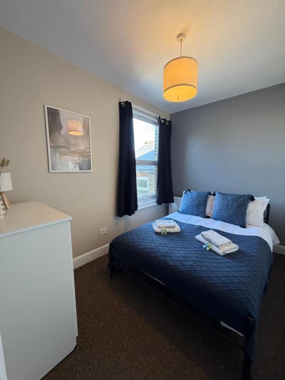 a bedroom with a bed with blue sheets and a window at Elegant Flat in Ealing in Greenford