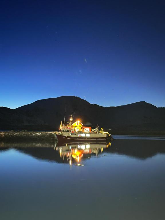 a boat sitting on the water at night at Lysbøen Bua in Ramberg