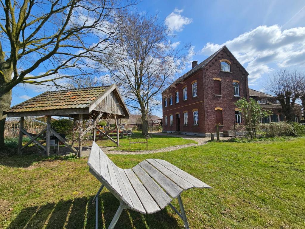 a wooden bench sitting in the grass in front of a building at Das alte Herrenhaus auf dem Bio-Bauernhof in Kevelaer