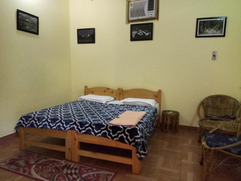 a bedroom with a bed and a chair at corbett motel in Rāmnagar
