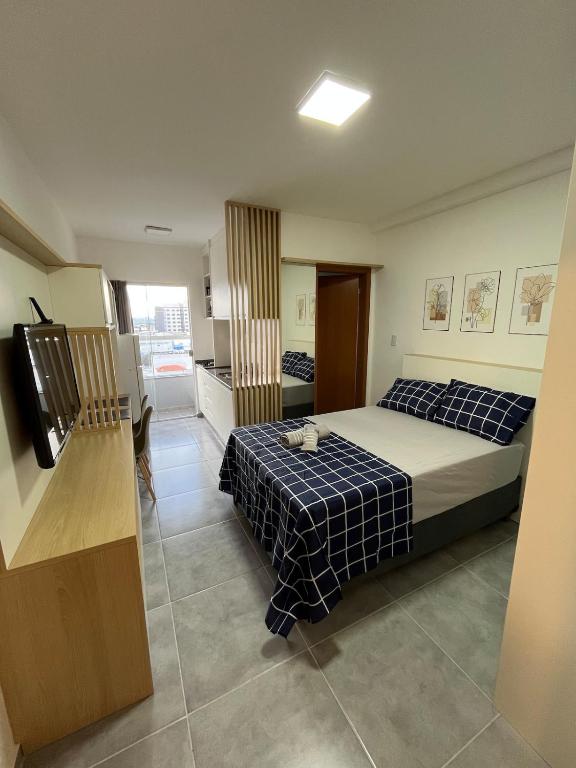 a bedroom with two beds and a television in it at Studio Aura in Barbacena