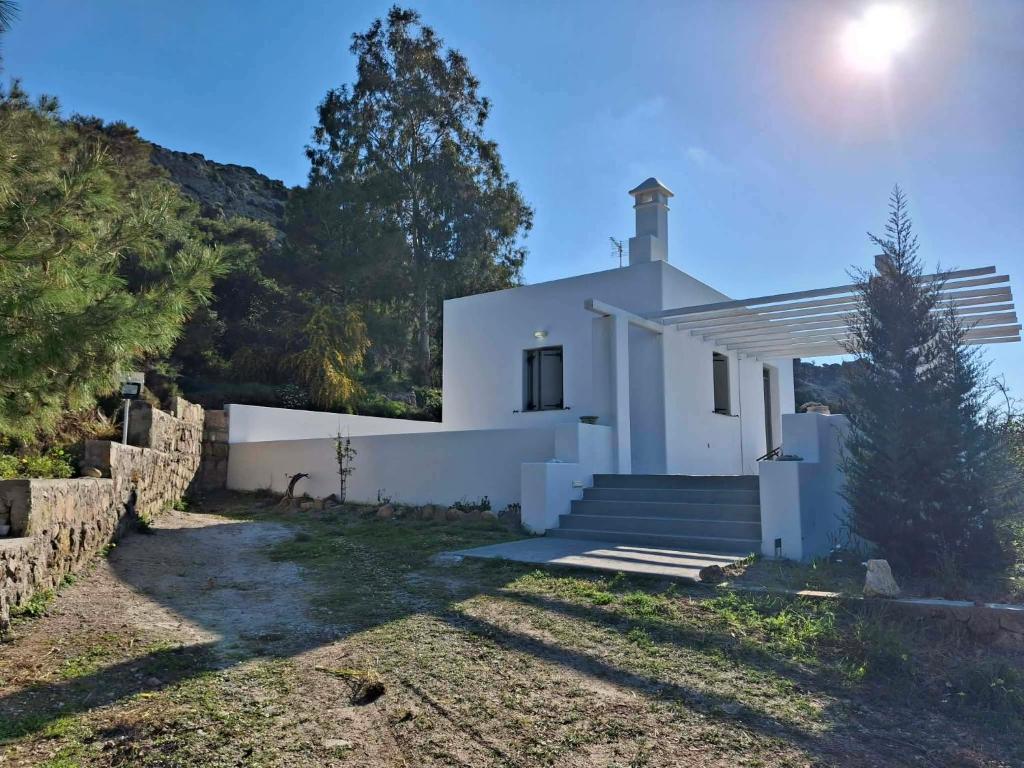 a white church with a hill in the background at Sophia's Ralaki Cottage in Ralaki
