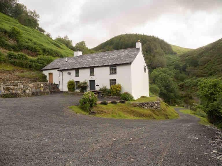 a white house in the middle of a mountain at Cwm Ffernol in Machynlleth