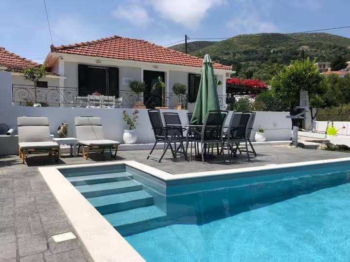 a house with a swimming pool with chairs and a table at Lilac House Kefalonia in Ratzaklíon