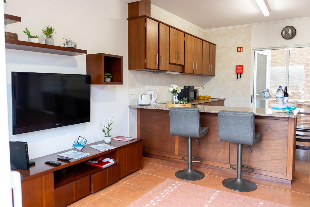 a kitchen with a bar with two chairs and a flat screen tv at Furnas Panorama House in Furnas
