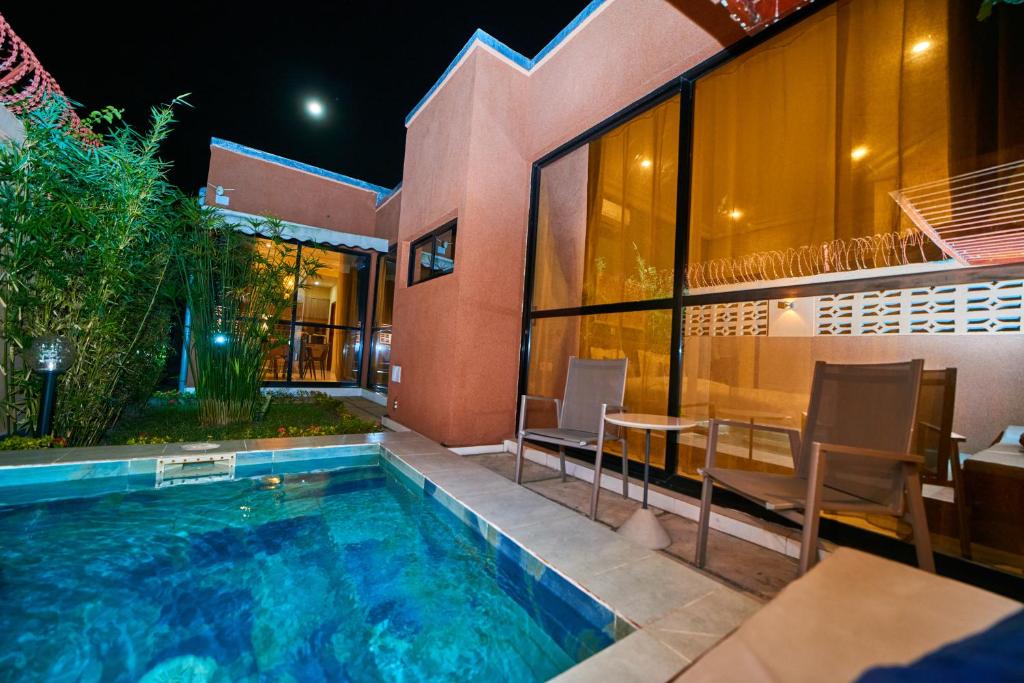 a pool with a table and chairs next to a building at Résidence Akia - Jacuzzi privé & détente moderne in Pointe-Noire