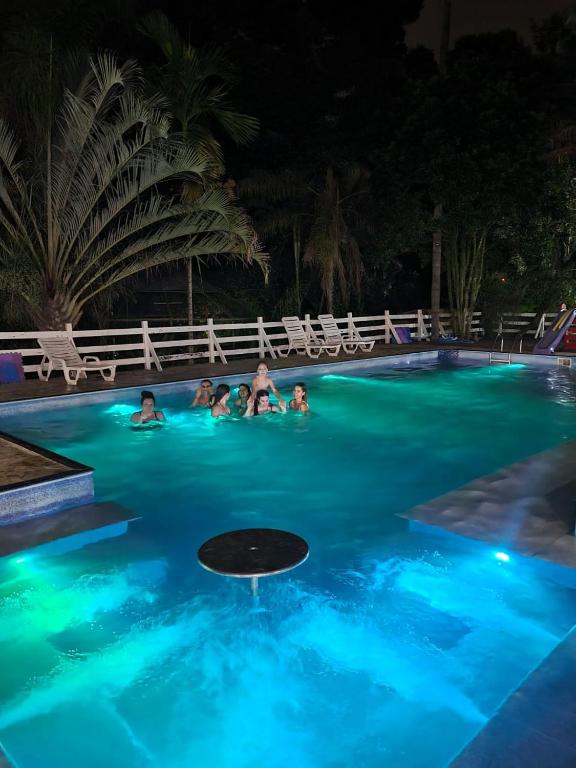 a group of people in a swimming pool at night at Ecos Jatobá - Refúgio à 12 km do Santuário de Aparecida in Guaratinguetá