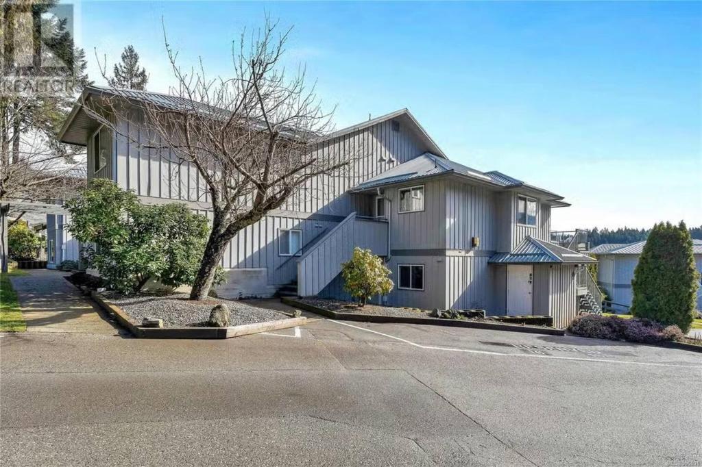 a large white house with a tree in a driveway at Lakefront Condo and Beach in Shawnigan Lake