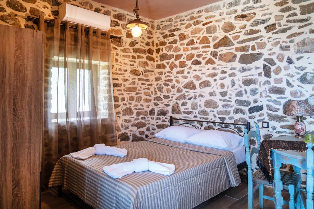 a bedroom with two beds and a stone wall at Oliva Mare II in Agia Fotia