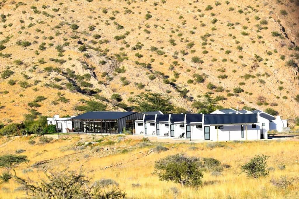 a white building on a hill in a field at Achab chalets in Usakos