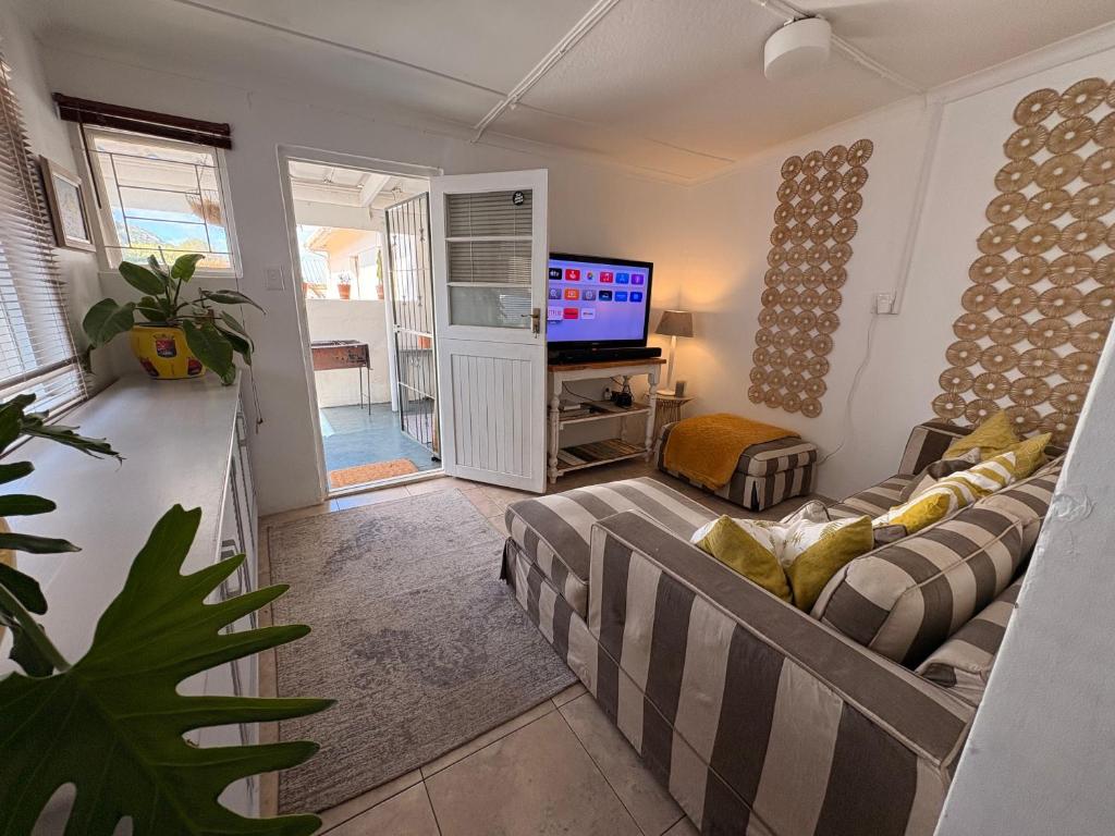 a living room with a couch and a television at Cosy Coastal Hideaway in Hermanus