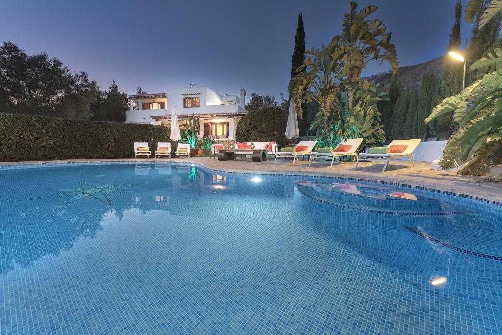 a swimming pool with chairs and a house in the background at Can Juanito in Playa d'en Bossa