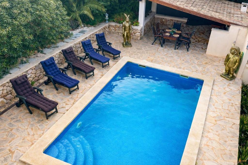 a large swimming pool with chairs and a table at Casa Baleares TS SL in Cala Santanyi