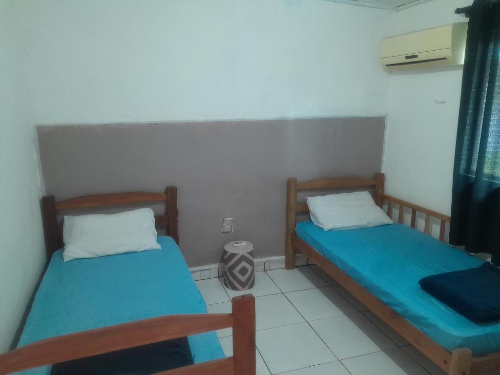 two beds in a small room with blue sheets at Guardião in Porto Velho