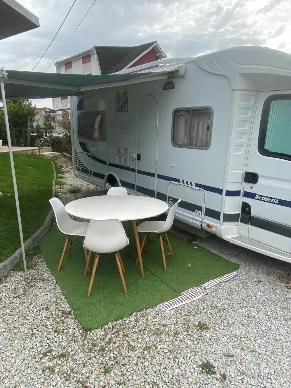 a white table and chairs in front of a trailer at Autocaravana Dethleffs Globetrotter in Viana do Castelo