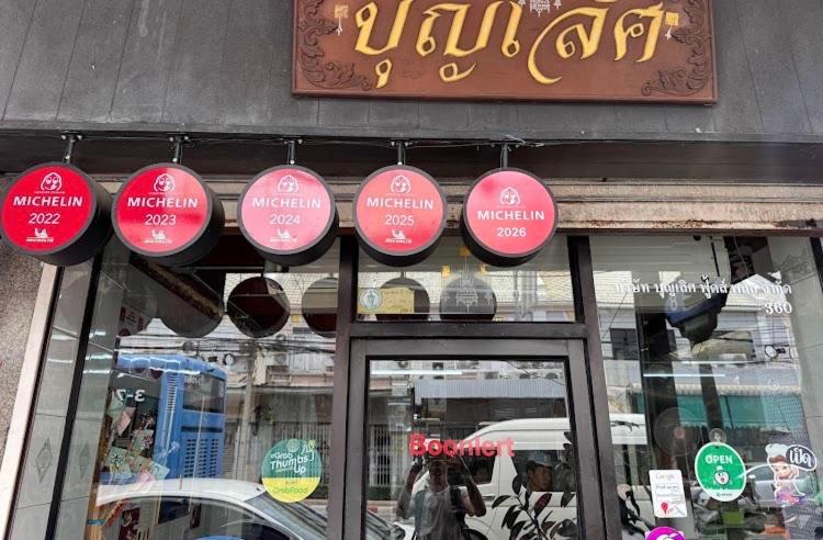 a store front with red and white signs on the window at Boonlert Egg Noodle in Bangkok