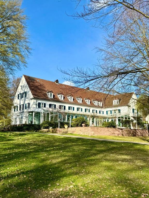 a large white house with a large yard at Parkhotel Steimker Berg Wolfsburg in Wolfsburg