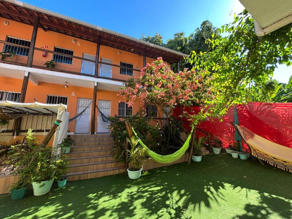 a hammock in front of a house with potted plants at Village enseada do castelo-com carregador de carros eletricos in Praia do Forte