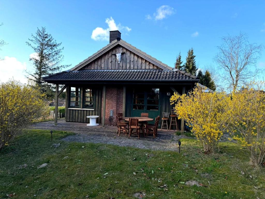 a house with a table and chairs in a yard at Wooden Western Lodge Tiny Haus in Brekendorf