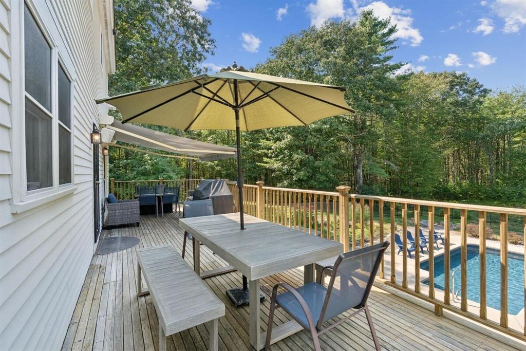 a wooden deck with a table and an umbrella at Wildflower Retreat in Kennebunk