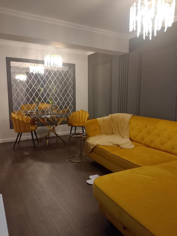 a living room with a yellow couch and a table at Gloria Golden Suite- Luxury&Designe Experience in Oradea