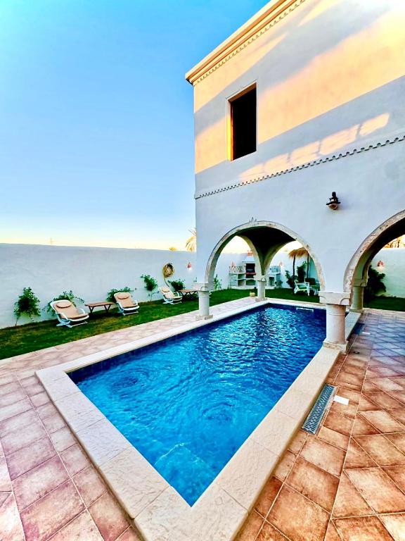 a house with a swimming pool in front of the ocean at Dar Sofien Erriadh Djerba in Erriadh