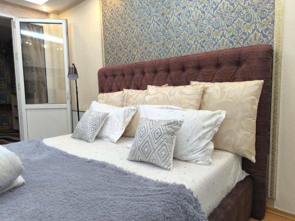 a bed with a bunch of pillows on it at Апартаменты на Бараева in Astana